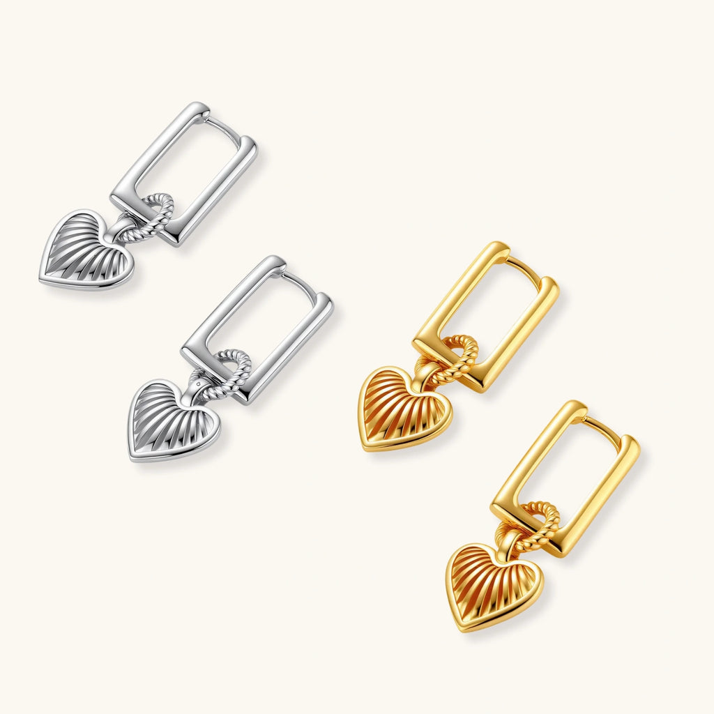 Gold-plated huggie earrings with textured heart charms featuring radiating sunburst patterns on white background.