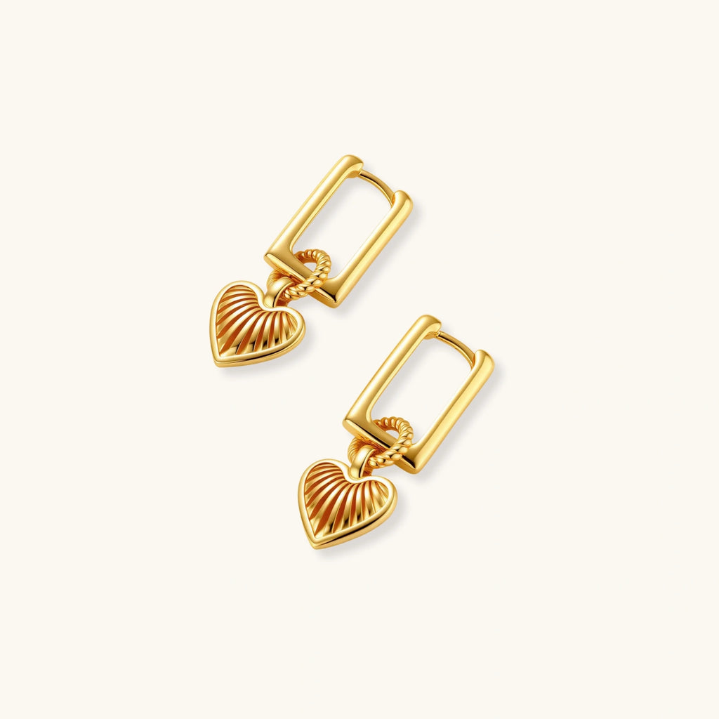 Gold-plated huggie earrings with textured heart charms featuring radiating sunburst patterns on white background.